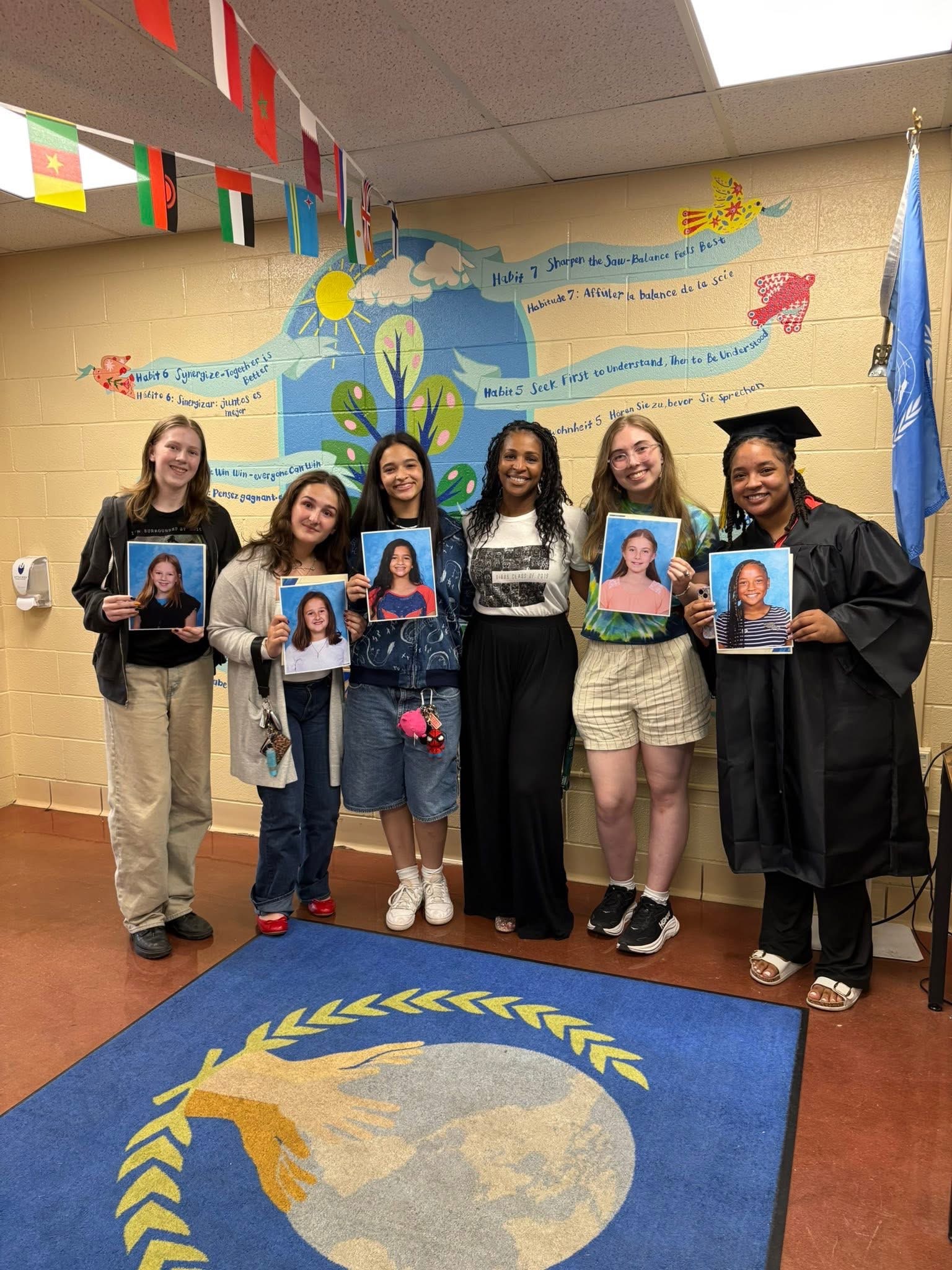 Former Gibbs students holding up their elementary school portraits with a Gibbs staff member