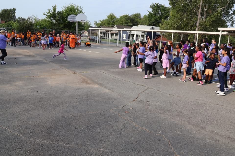 Gibbs students gathered by house in orange and purple shirts during an outdoor pep rally.